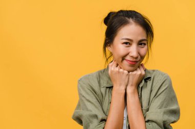 Olumlu ifadeli genç Asyalı bayan, geniş bir gülümseme, günlük kıyafetler giymiş ve sarı arka plandan kameraya bakıyor. Mutlu, sevimli, mutlu kadın başarıya sevinir. Yüz ifadesi kavramı.