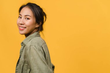 Olumlu ifadeli genç Asyalı bayan, geniş bir gülümseme, günlük kıyafetler giymiş ve sarı arka plandan kameraya bakıyor. Mutlu, sevimli, mutlu kadın başarıya sevinir. Yüz ifadesi kavramı.