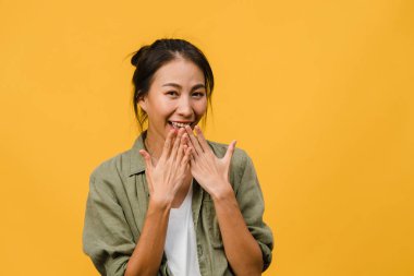 Olumlu ifadeli genç Asyalı bayan, geniş bir gülümseme, günlük kıyafetler giymiş ve sarı arka plandan kameraya bakıyor. Mutlu, sevimli, mutlu kadın başarıya sevinir. Yüz ifadesi kavramı.