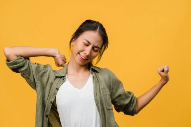 Olumlu ifadeli, neşeli ve heyecan verici, sarı arka planda boş alan olan günlük giysiler giymiş genç Asyalı bayan. Mutlu, sevimli, mutlu kadın başarıya sevinir. Yüz ifadesi kavramı.