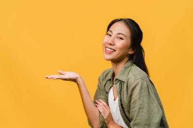 Neşeli bir ifadeyle gülümseyen Asyalı genç bir kadının portresi boş bir alanda, sarı arka planda izole edilmiş bir kameraya bakarak inanılmaz bir şey gösteriyor. Yüz ifadesi kavramı.