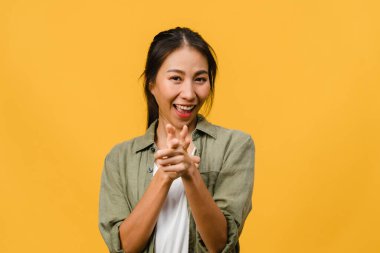 Neşeli bir ifadeyle gülümseyen Asyalı genç bir kadının portresi boş bir alanda, sarı arka planda izole edilmiş bir kameraya bakarak inanılmaz bir şey gösteriyor. Yüz ifadesi kavramı.