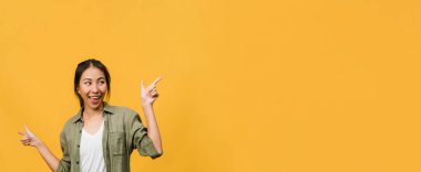 Neşeli bir ifadeyle gülümseyen Asyalı genç bir kadının portresi, boş bir alanda günlük giysiler içinde ve sarı arka planda izole bir şekilde duran inanılmaz bir şey gösteriyor. Kopyalama alanı olan panoramik pankart.