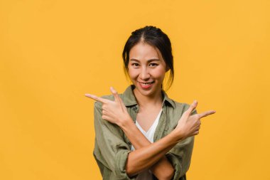 Neşeli bir ifadeyle gülümseyen Asyalı genç bir kadının portresi boş bir alanda, sarı arka planda izole edilmiş bir kameraya bakarak inanılmaz bir şey gösteriyor. Yüz ifadesi kavramı.