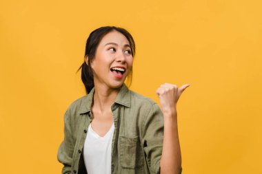 Neşeli bir ifadeyle gülümseyen Asyalı genç bir kadının portresi, boş bir alanda günlük giysiler içinde ve sarı arka planda izole bir şekilde duran inanılmaz bir şey gösteriyor. Yüz ifadesi kavramı.