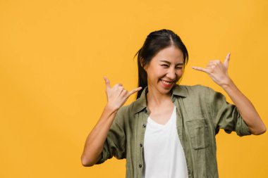 Olumlu ifadeli genç Asyalı bayan, geniş bir gülümseme, günlük kıyafetler giymiş ve sarı arka plandan kameraya bakıyor. Mutlu, sevimli, mutlu kadın başarıya sevinir. Yüz ifadesi kavramı.