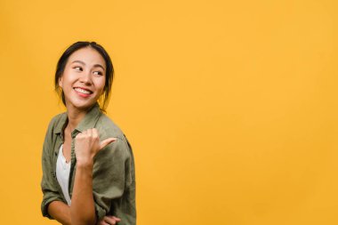Neşeli bir ifadeyle gülümseyen Asyalı genç bir kadının portresi, boş bir alanda günlük giysiler içinde ve sarı arka planda izole bir şekilde duran inanılmaz bir şey gösteriyor. Yüz ifadesi kavramı.