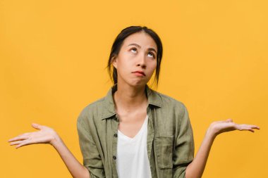 Asyalı genç bir kadının portresi, olumsuz ifadeli, heyecanlı çığlık atan, ağlayan, duygusal sinirli, sarı arka planda izole edilmiş, boş fotokopi alanı olan. Yüz ifadesi kavramı.