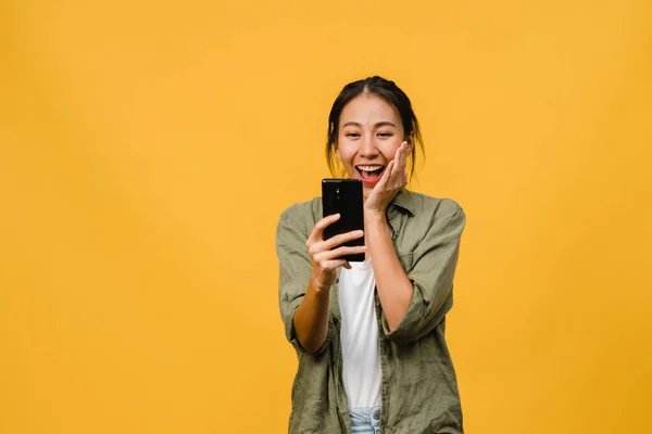 Overrasket Ung Asiatisk Dame Som Bruker Mobiltelefon Med Positivt Uttrykk stockfoto