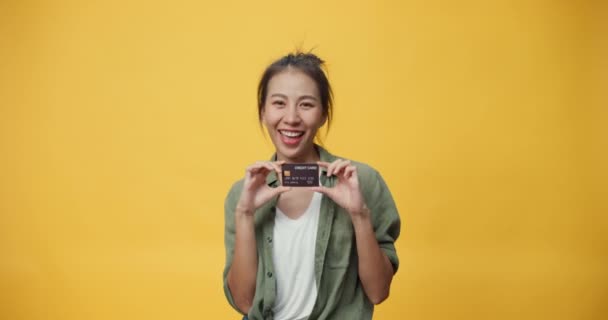 漂亮迷人的亚洲年轻人孤家寡人手里拿着信用卡惊奇地在线购物 成功地支付了黄色背景的钱 模拟复制空间 持有借记卡概念 — 图库视频影像