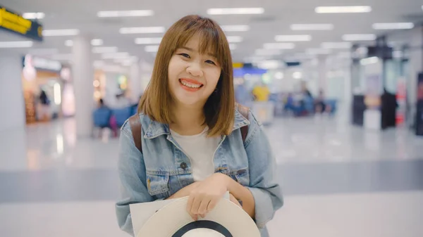 幸せなアジアの女性の女性観光客の休暇で旅行する準備ができて 国際空港のターミナルにとどまっている間カメラに笑顔します 空港のコンセプトのライフ スタイル女性の幸せな休日 — ストック写真