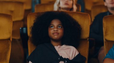 Çekici, neşeli, Afrikalı bir kız sinemada film izlerken gülüyor. Yaşam tarzı eğlence konsepti.