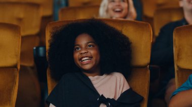 Çekici, neşeli, Afrikalı bir kız sinemada film izlerken gülüyor. Yaşam tarzı eğlence konsepti.