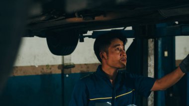 Profesyonel araba tamircisi, benzin ve motor kontrollerini tamirat gecesinde kaldırılan otomobilin üzerine yapıyor. Araba tamir eden Asyalı yetenekli bir adam..