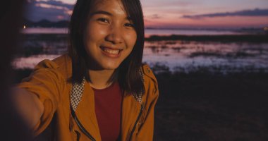 Neşeli gezgin Asya 'lı bayan sırt çantasıyla video vlog kaydediyor sosyal medyada canlı yayında gece kampında kamp yapıyor. Kız mutlu tatiller. Yaşam tarzı seyahat ve rahatlama.