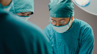Genç Asyalı asistanlar ve hemşireler hastane ameliyathanesinde hastaya invazif ameliyat yapıyorlar. Profesyonel cerrah, sağlık ve tıbbi konseptten oluşan farklı bir ekip..