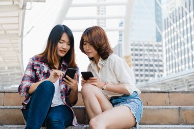 Bir grup Asyalı kadın yön bulmak için akıllı telefon kullanıyor ve Tayland 'ın Bangkok kentindeki şehir haritasına bakıyorlar. Tayland konseptinde yaşam tarzı turist seyahati.