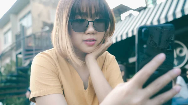 在户外咖啡店用手机旅游的亚洲妇女 年轻的日本亚洲女孩使用智能手机检查社交媒体 并与社交网络中的朋友进行短信 享受假期旅行 — 图库照片