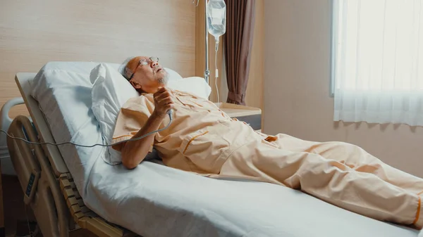 伤心的资深亚洲人心脏病发作躺在病床上 按下紧急按钮 一个年老体衰的病人躺在一家诊所里住院治疗 健康保险或招待费概念 — 图库照片