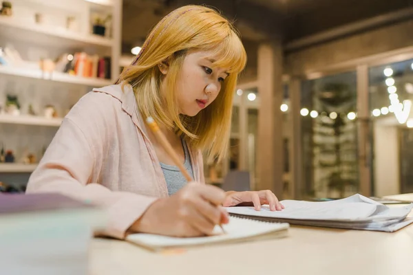 亚洲女学生在大学图书馆看书 在大学校园加班之夜 年轻的女大学生在课桌上做作业 努力学习知识 — 图库照片
