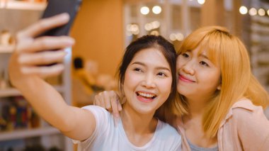 Neşeli genç Asyalı arkadaş bir kafede cep telefonu kullanarak selfie çekiyor. Restoranda ya da kafede birlikte iki çekici Asyalı kız. Tatil aktivitesi, ya da modern yaşam tarzı konsepti.