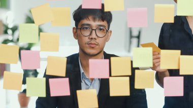 Bir grup Asyalı yaratıcı adam ayna panosunun önünde beyin fırtınası yapıyor. Çalışan genç profesyonel iş ekibi strateji, iş durumu, tavan arası ofis konsepti oluşturma.