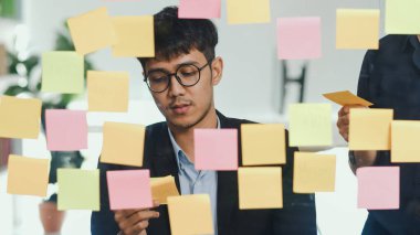 Bir grup Asyalı yaratıcı adam ayna panosunun önünde beyin fırtınası yapıyor. Çalışan genç profesyonel iş ekibi strateji, iş durumu, tavan arası ofis konsepti oluşturma.