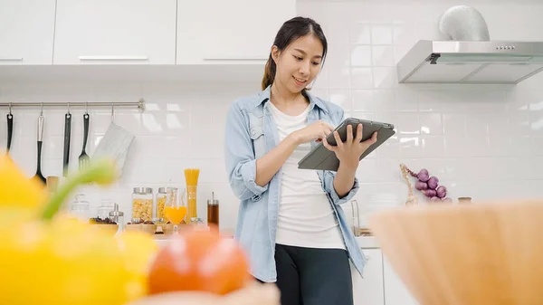 Onnellinen Aasialainen Nainen Joka Käyttää Tablettia Reseptin Etsimiseen Ruoanvalmistuksessa Keittiössä — kuvapankkivalokuva