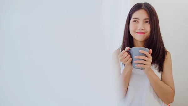 Lykkelig Asiatisk Kvinne Som Smiler Drikker Kaffe Ved Vinduet Soverommet – stockfoto