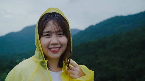 若いアジア女性感じ幸せな演奏の雨の森付近を歩いてレインコートを着用しながらの ライフ スタイルの女性と雨の日のリラックスをお楽しみいただけます — ストック写真