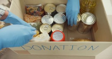 Bir grup genç Asyalı gönüllü, hayır kurumunda çalışırken yiyecek ve içecek paketleyip bağış kutularına bağışta bulunan eldiven giyiyor. Sosyal hizmet görevlisi, gıda bankası ve koronavirüs konsepti.