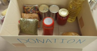 Bir grup genç Asyalı gönüllü, hayır kurumunda çalışırken yiyecek ve içecek paketleyip bağış kutularına bağışta bulunan eldiven giyiyor. Sosyal hizmet görevlisi, gıda bankası ve koronavirüs konsepti.