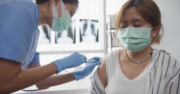 10代の少女に接種したCovid 19またはインフルエンザウイルスワクチンを投与した若いアジアの女性看護師は 健康クリニックや病院でウイルス病から顔マスク保護を着用してください 閉じるか 閉じるショット — ストック動画