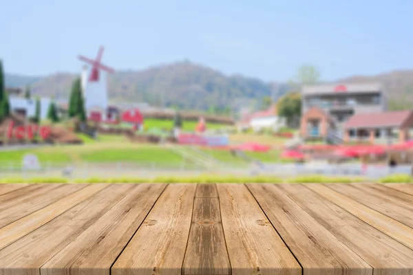 Holzbrett leerer Tisch vor verschwommenem Hintergrund. Perspektive braunes Holz über verschwimmen schöne Resort und Landschaft Berg mit Bokeh - kann für Display- oder Montage-Produkte verwendet werden. — Stockfoto