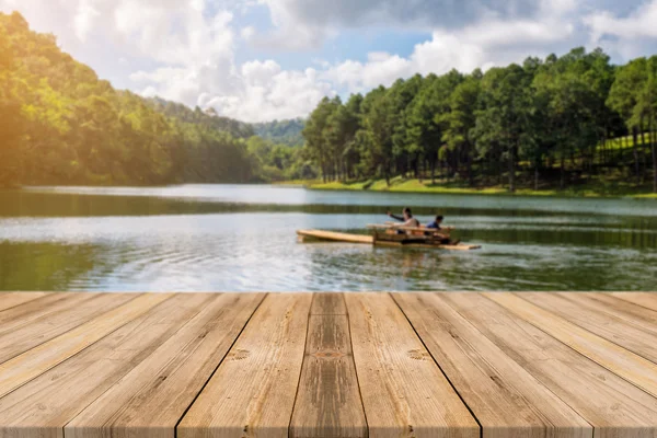 Holzbrett leerer Tisch vor verschwommenem Hintergrund. Perspektive braunes Holz über verschwommenem See im Wald - kann zur Anzeige oder Montage Ihrer Produkte verwendet werden. Frühlingszeit. — Stockfoto