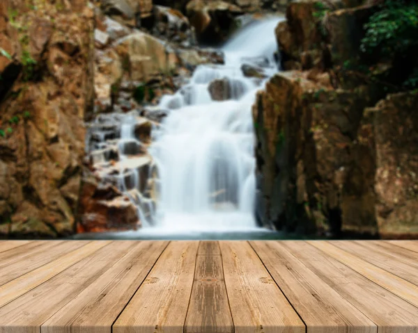 Holzbrett leerer Tisch vor verschwommenem Hintergrund. Perspektive braunes Holz über verschwommenem Wasserfall im Wald - kann zur Anzeige oder Montage Ihrer Produkte verwendet werden. Frühlingszeit. — Stockfoto