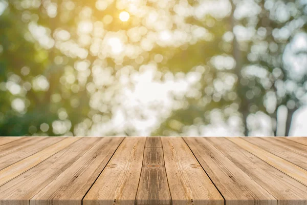 Placa de madeira mesa vazia na frente do fundo borrado. Madeira castanha em perspectiva sobre árvores desfocadas na floresta - pode ser usada para exibir ou montar seus produtos. imagem filtrada vintage . — Fotografia de Stock