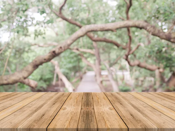 Holzbrett leerer Tisch vor verschwommenem Hintergrund. Perspektive braunes Holz über unscharfe Bäume im Wald - kann für die Anzeige oder Montage Ihrer Produkte verwendet werden. Vintage gefiltertes Bild. — Stockfoto