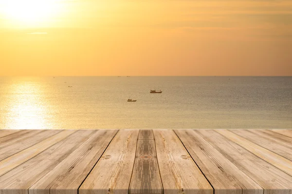 Tablă de lemn masă goală în fața fundalului apus de soare. Podeaua prospectivă din lemn pe mare și pe cer poate fi folosită pentru afișarea sau montarea produselor dvs. plajă și concepte de vară . Fotografie de stoc