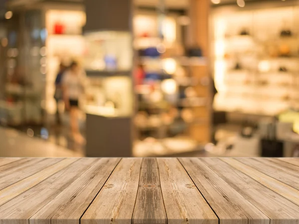 Tomt bord av tre foran utydelig bakgrunn. Perspektiv brun trevare over lysbutikkene på kjøpesenteret - kan brukes til visning eller montasje av produktene dine . stockfoto