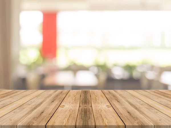 Σανίδα άδειο τραπέζι μπροστά θολή φόντο. Προοπτική καφέ ξύλο πάνω από blur σε καφενείο - μπορεί να χρησιμοποιηθεί για την επίδειξη ή μοντάζ σας προϊόντα. Χλευάσουμε επάνω σας προϊόντα. Εικόνα Αρχείου