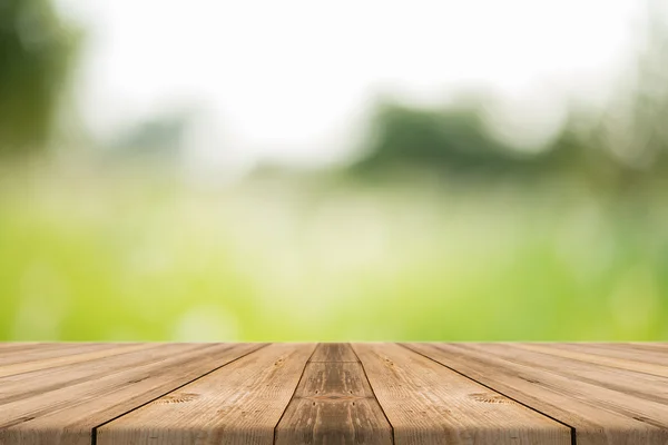 Tablero de madera mesa vacía en frente de fondo borroso. Perspectiva de madera marrón sobre los árboles borrosos en el bosque - se puede utilizar para mostrar o montar o burlarse de sus productos. sus productos . — Foto de Stock