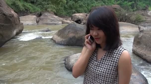 Mujer atractiva hablando en el teléfono celular por la hermosa cascada . — Vídeo de stock