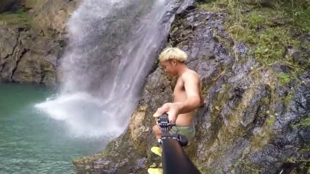 Hombre caminando ir a selfie cerca de cascada . — Vídeos de Stock