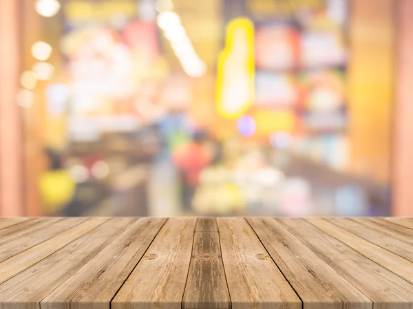 Tablero de madera mesa vacía en frente de fondo borroso. Perspectiva de madera marrón sobre desenfoque en la cafetería - se puede utilizar para la exhibición o montaje de sus productos.Prepárese para la exhibición del producto. — Foto de Stock