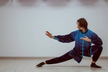 Çince kostüm giymiş Tai Chi öğretmeni çalışma odasında ders veriyor.