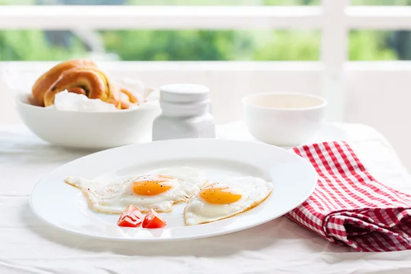 Homemade fried eggs with tomatoes and red kidney beans on a plate on a table with kitchen background, closeup — Stock Photo, Image