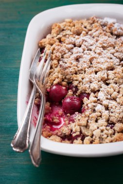  Yeşil ahşap arka planda buğday unu ve pudra şekerli ev yapımı vişneli turta.