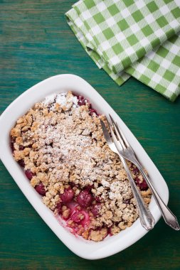  Yeşil ahşap arka planda buğday unu ve pudra şekerli ev yapımı vişneli turta.