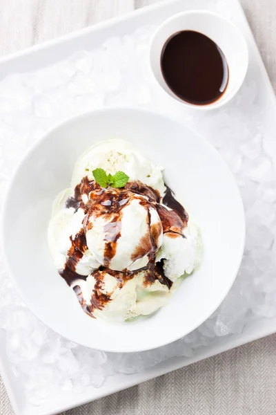 Gelato alla vaniglia e pistacchio con salsa al cioccolato in una ciotola su un piatto con ghiaccio — Foto Stock